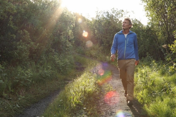 View of man following hiking path through woods
