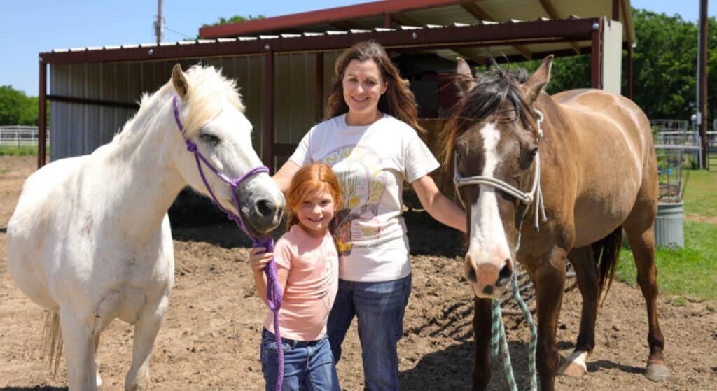 Breast cancer survivor Brooke Jayo and her daughter Harper hold their horses