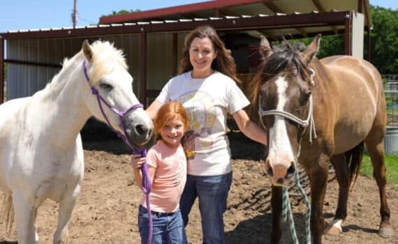 Breast cancer survivor Brooke Jayo and her daughter Harper hold their horses