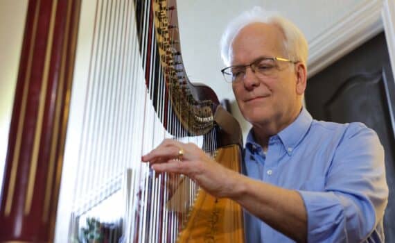 Rod Milton plays the harp in his Southlake home.