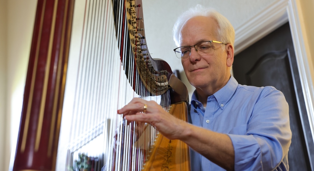 Rod Milton plays the harp in his Southlake home.