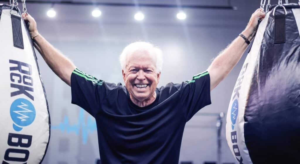 Steven Pratt poses between two punching bags in the gym where he trains.
