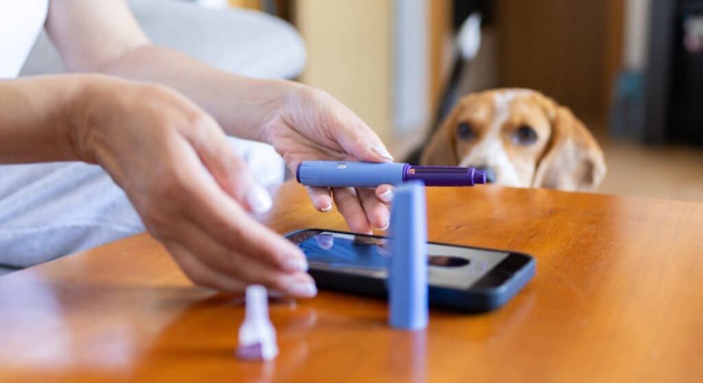 A woman consults her doctor by phone while using a GLP-1 injector.
