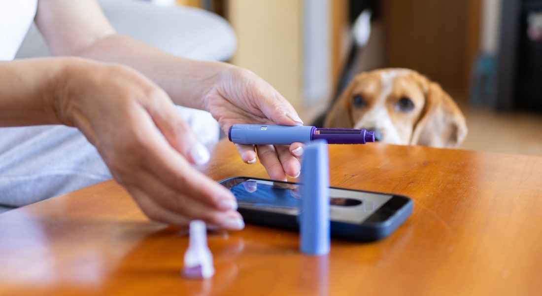 A woman consults her doctor by phone while using a GLP-1 injector.