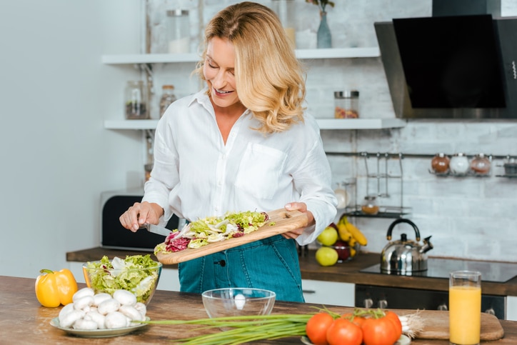 A woman makes a healthy salad in the kitchen.