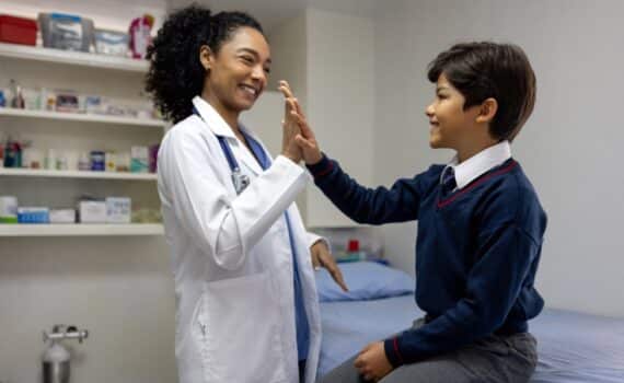 A school nurse gives a student a high-five in her office.