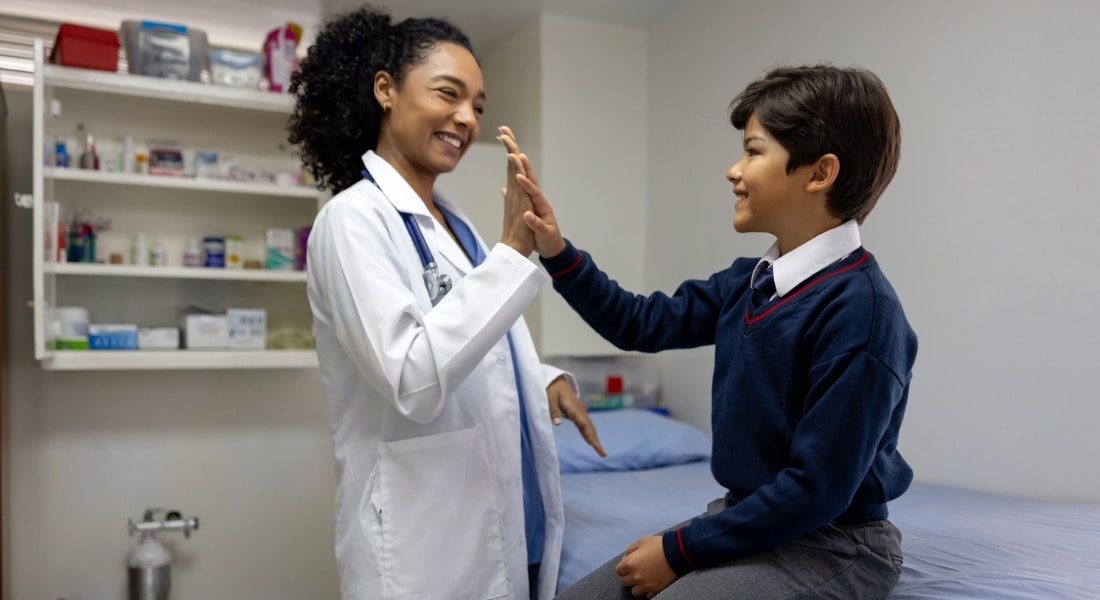 A school nurse gives a student a high-five in her office.