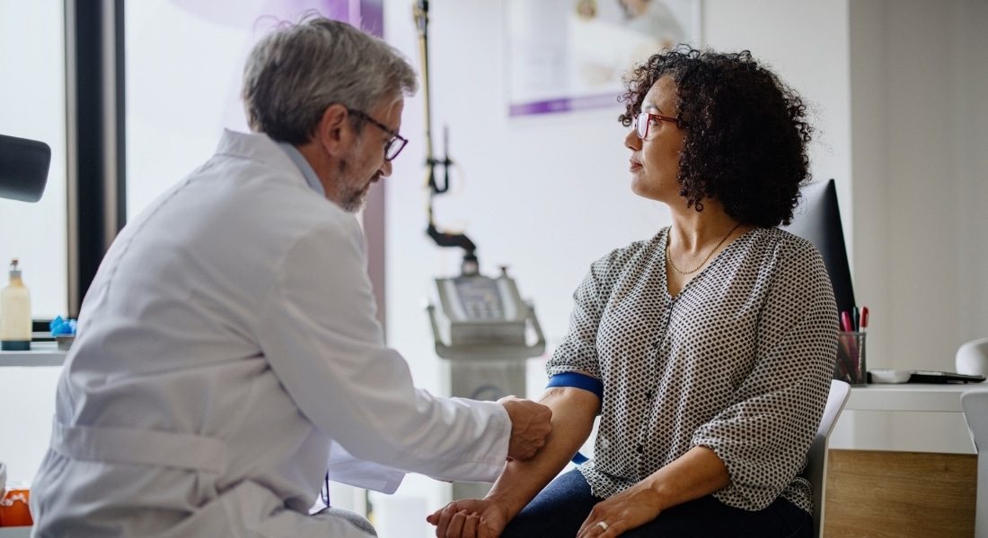A doctor takes a blood test from a female patient.