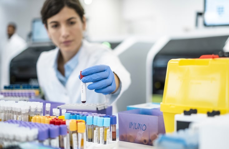 A lab technician in a white coat meticulously analyzes samples with precise equipment, surrounded by organized vials in a professional laboratory setting.