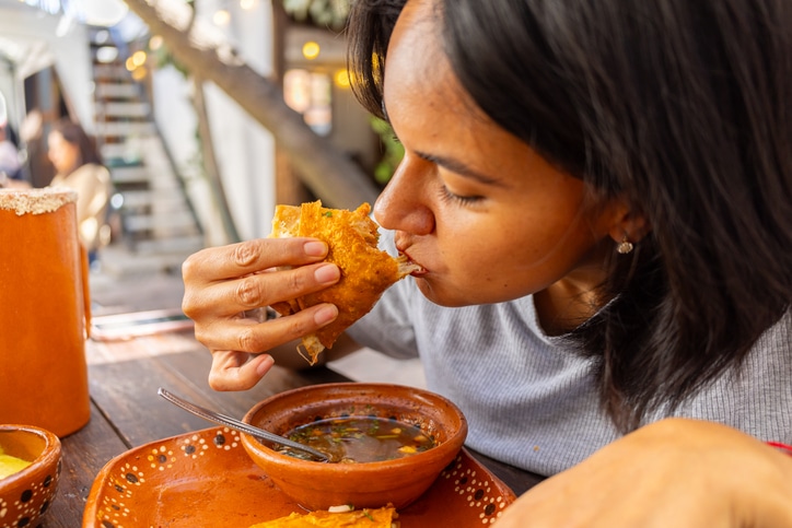 Woman eating delicious birria Mexican food