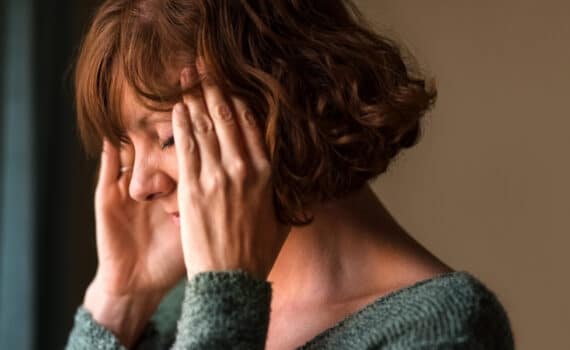 A woman in perimenopause holds her hands to her temples whole dealing with brain fog.