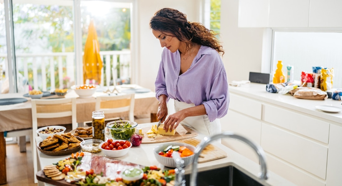 A woman in her 40s prepares a meal in her kitchen