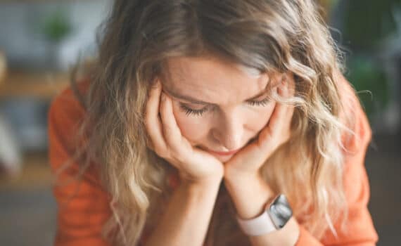 A woman with her head in her hands while suffering from anxiety during perimenopause