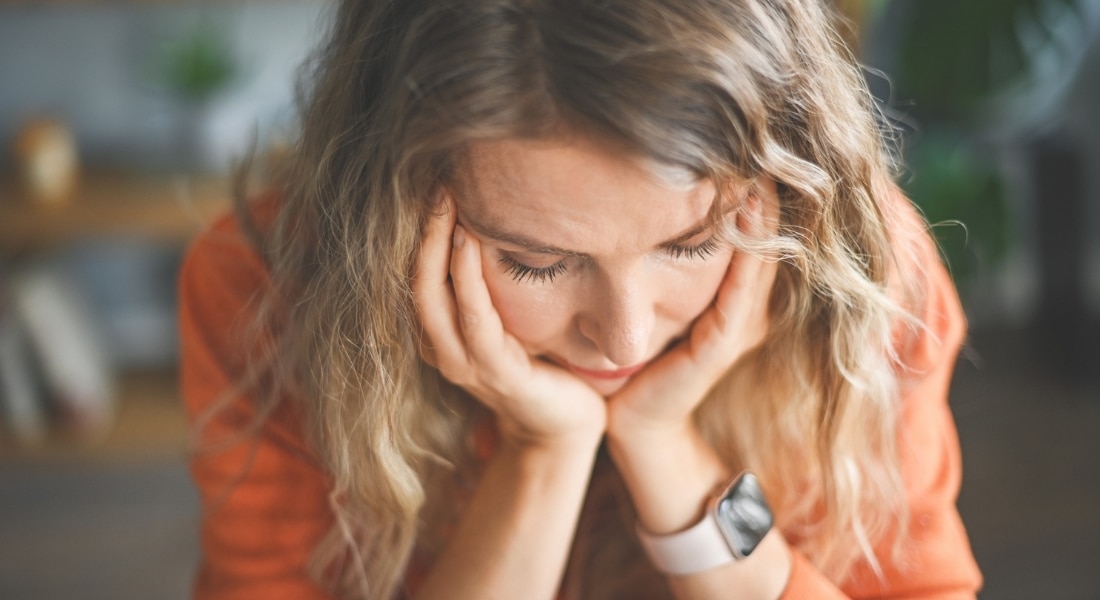 A woman with her head in her hands while suffering from anxiety during perimenopause