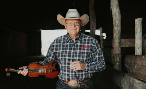 Pake McEntire holds his fiddle in a barn at his ranch on Oklahoma.