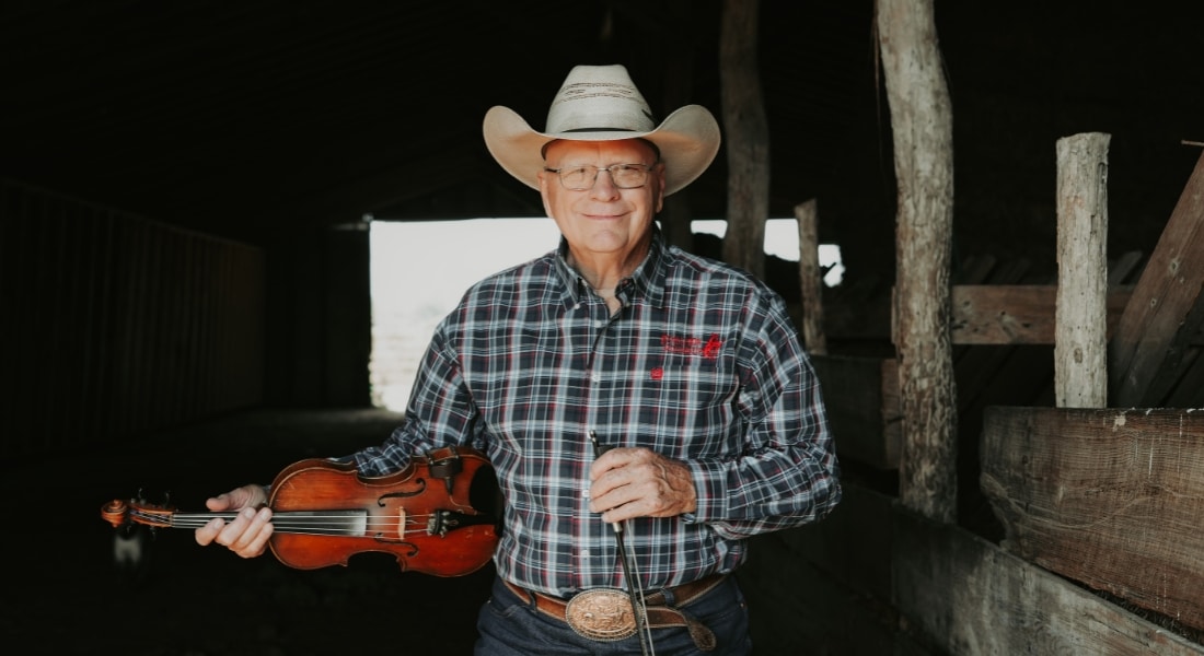 Pake McEntire holds his fiddle in a barn at his ranch on Oklahoma.