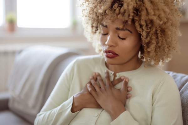 A woman in her 40s clutches her chest in distress.