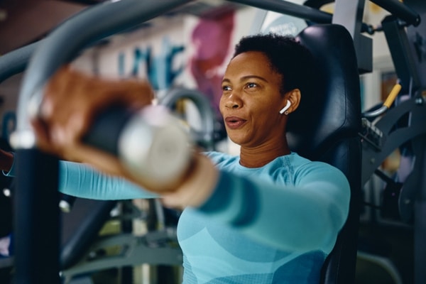 A middle age woman lifts weights in a gym.