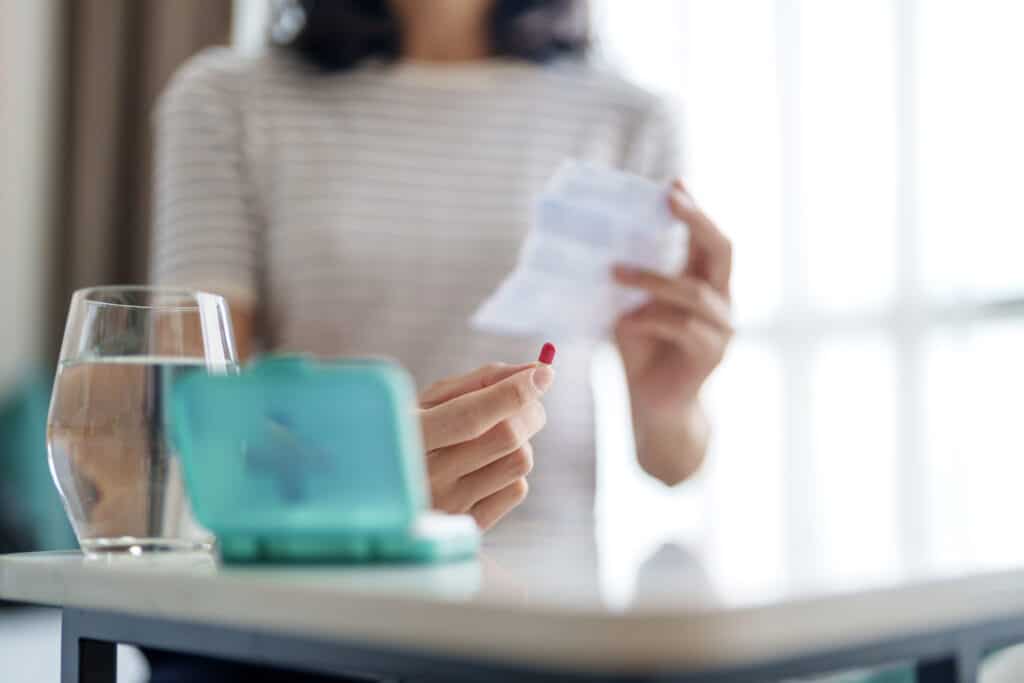 Close-up of an Asian woman carefully reviewing the patient information leaflet for her medication, ensuring she thoroughly understands the prescribed medicine and its usage.