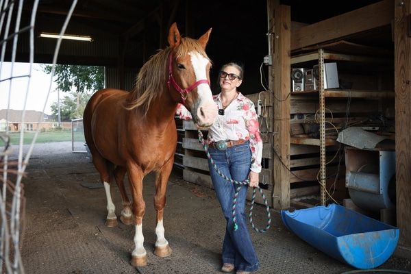 Amy Yoste stands next to her horse Holmes in a barn at her Celina home.