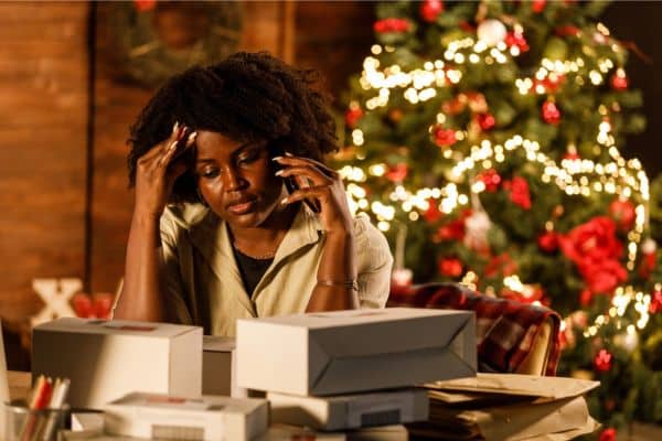 Overwhelmed young woman working for Christmas holidays, talking on the phone at her desk