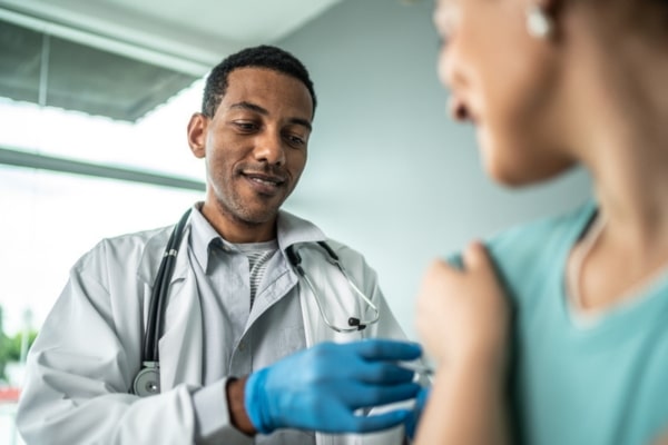 A doctor administers a flu vaccine to a woman patient.