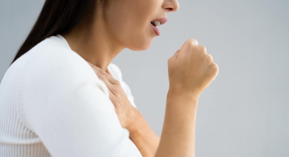 Unrecognizable woman coughing while suffering with GERD