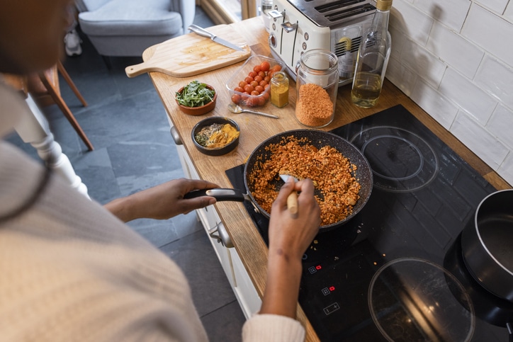 An over the shoulder shot of a young woman maintaining her sustainable living by preparing a vegan meal in the kitchen 