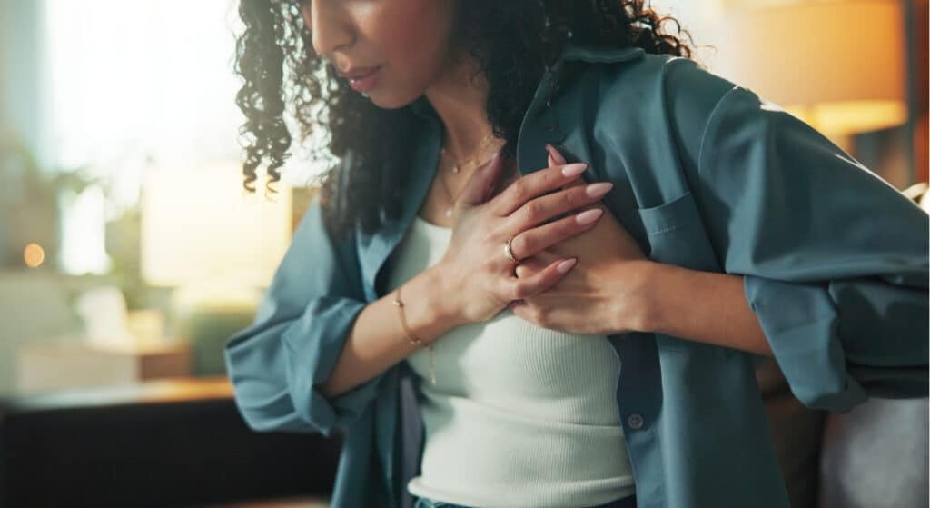 A woman sitting on a sofa clutches her chest