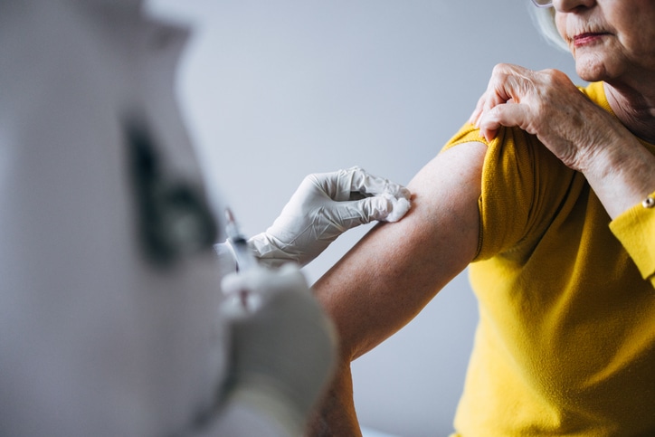 Healthcare professional administering a vaccination to an elderly woman. Focus on promoting health awareness, patient care, and medical safety for senior citizens. The image captures a moment of routine healthcare interaction.