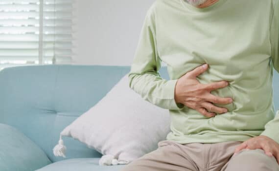 A middle-age man suffering from a hernia clutches his belly.