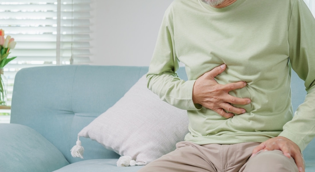 A middle-age man suffering from a hernia clutches his belly.