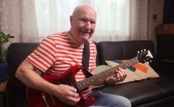 Gary Coots plays his electric guitar in his Arlington home.