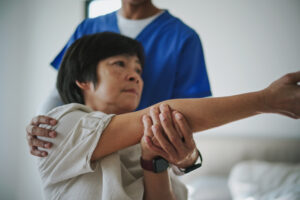 Asian mature woman is doing physical therapy with a professional therapist at home.