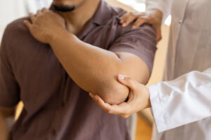 Physical therapist presses on the patient's shoulder to check for pain.