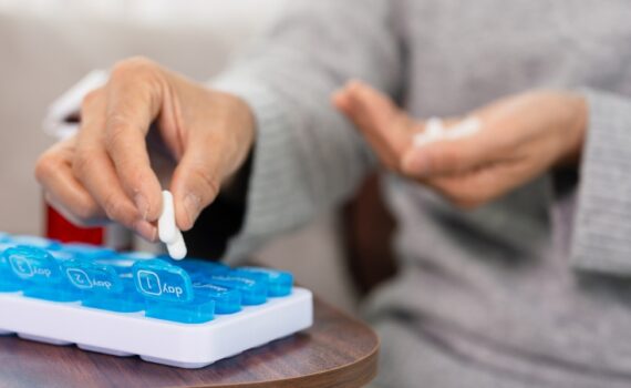 A woman fills a pill organizer with pain medication