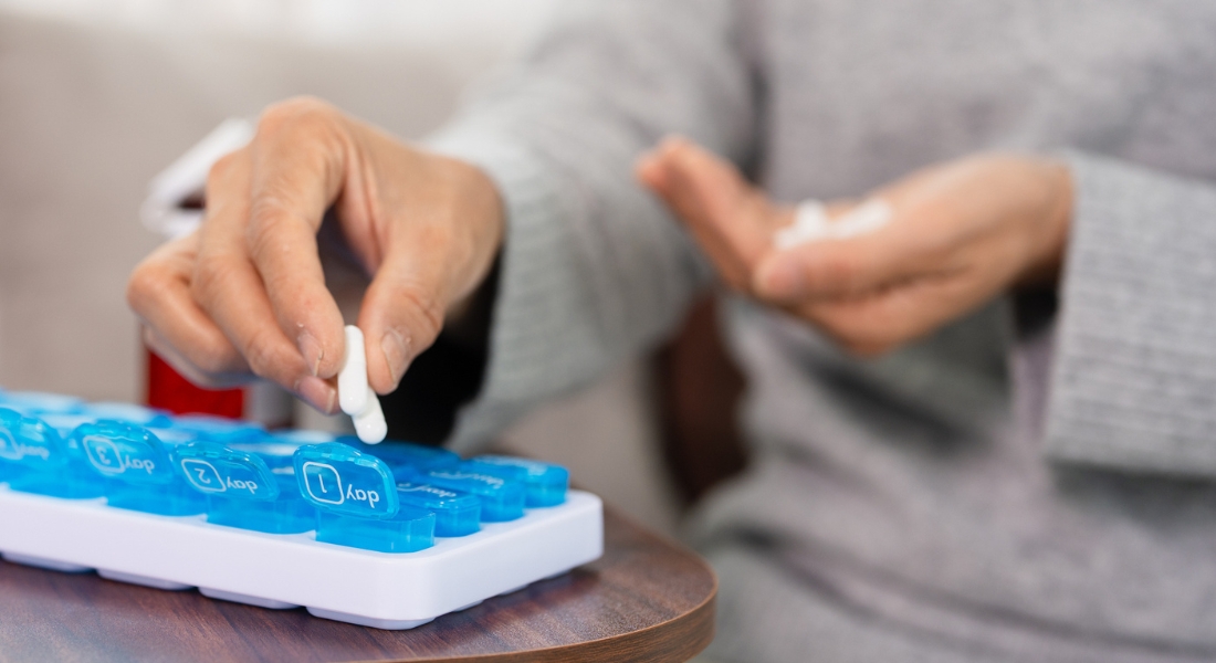 A woman fills a pill organizer with pain medication