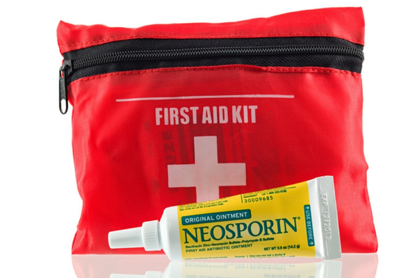 A tube of antibiotic ointment sits on a counter next to a first-aid kit.