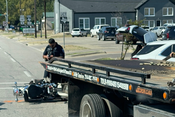 A police officer stands behind a tow truck examining Caleb Deleon’s motorcycle after his crash in Ennis.
